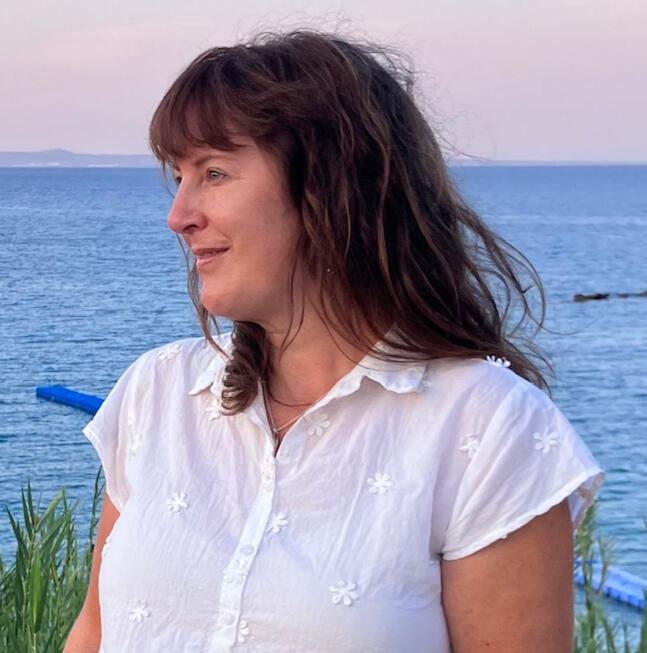 colour photo of author in a white top with the sea behind